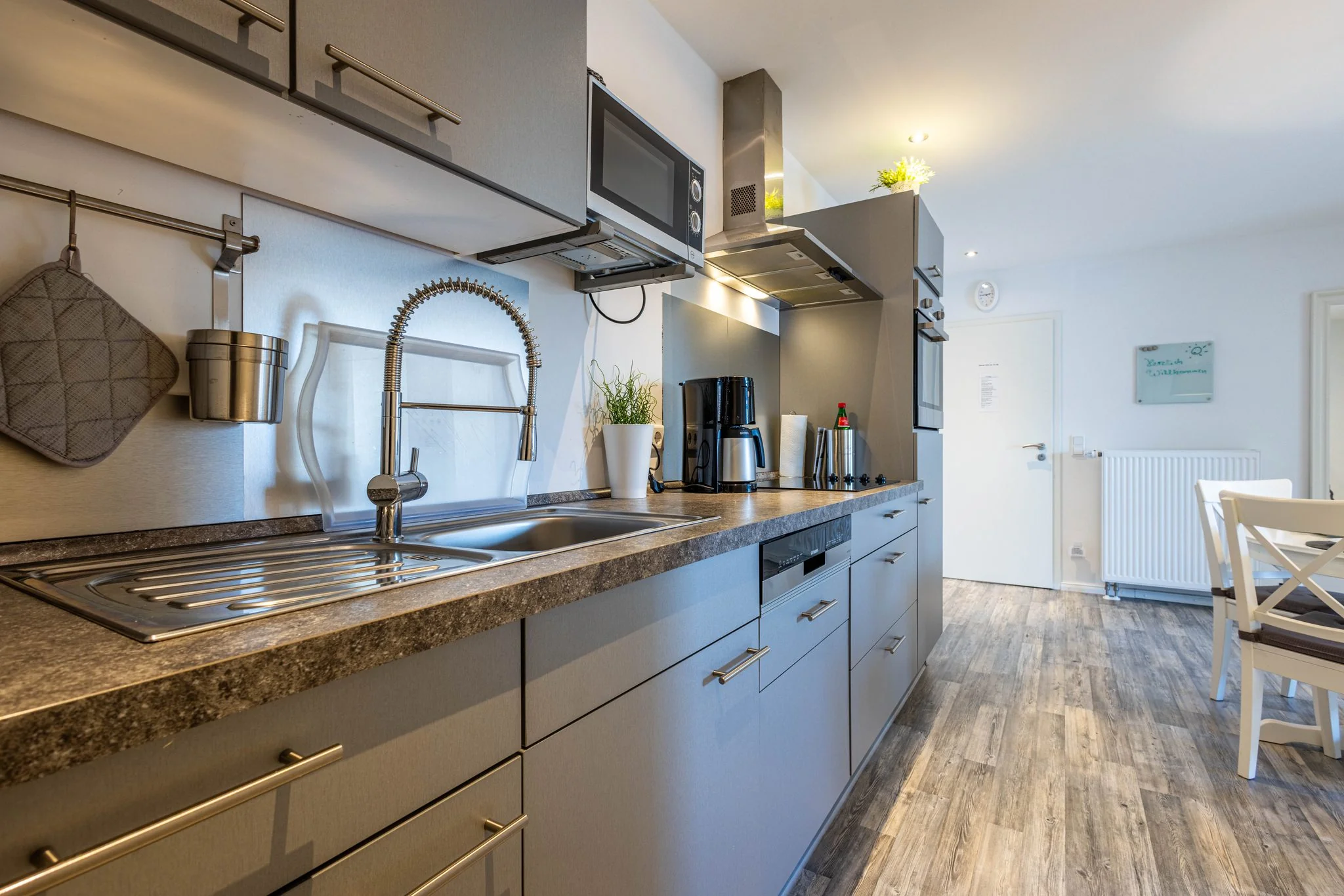 Moderne Ferienhaus-Küche mit Edelstahlspüle, Dunstabzugshaube, Mikrowelle und Esstisch