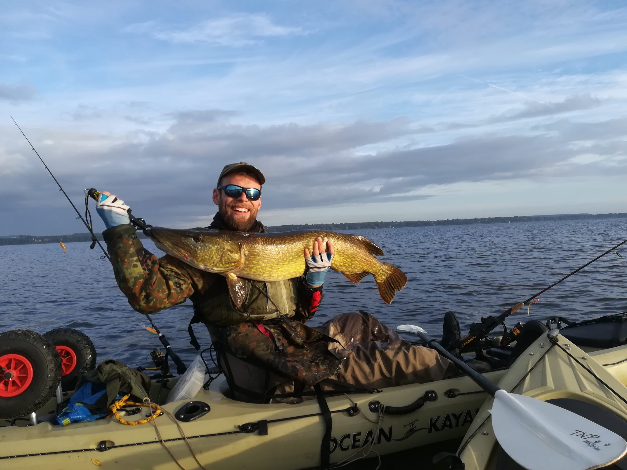 Angler im Kajak auf dem Wittensee hält stolz einen großen Hecht in die Kamera