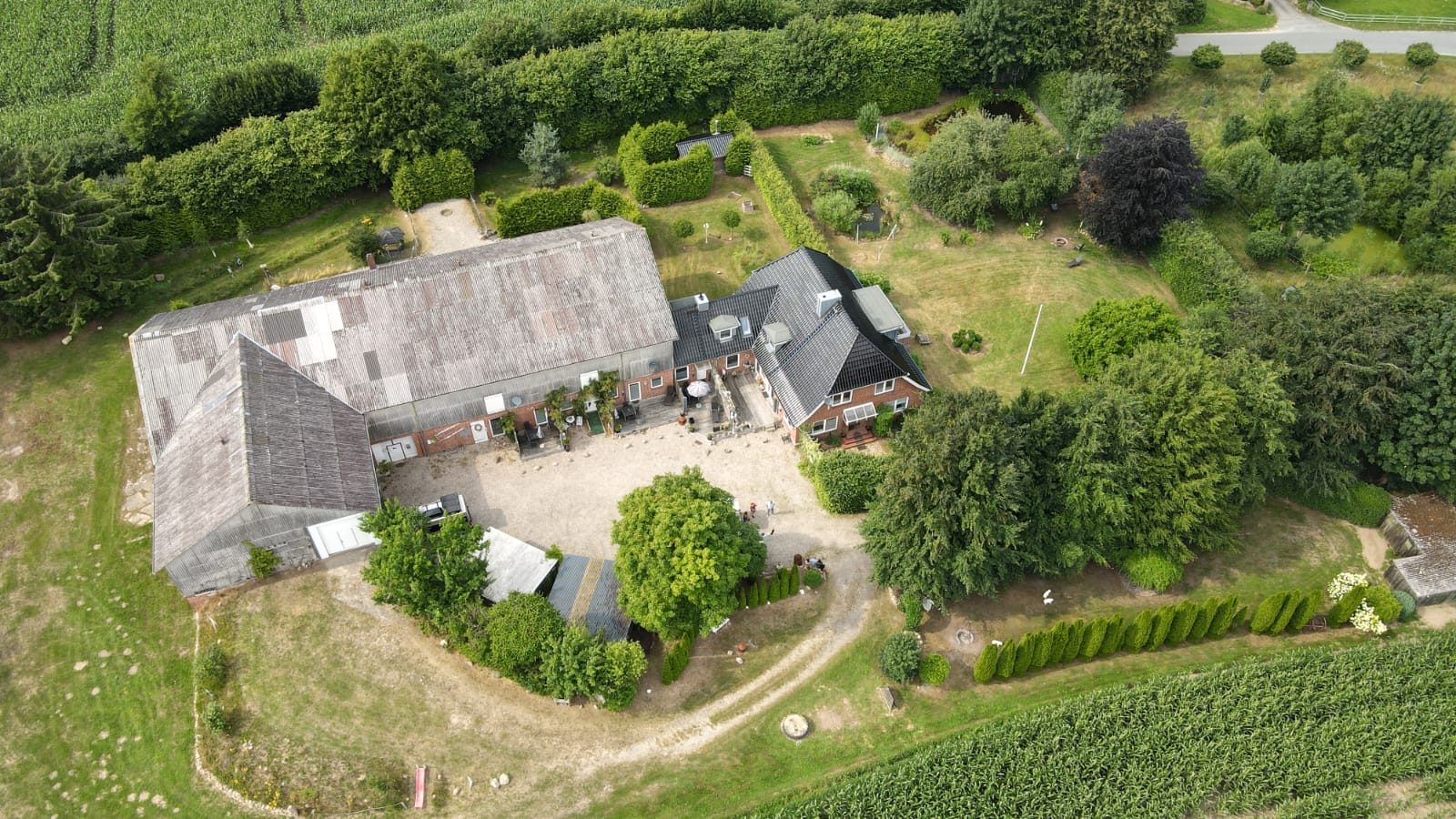 Luftaufnahme von Hof Gayenberg: Bauernhaus, großer Scheunenkomplex und Garten, umgeben von Feldern und Bäumen.