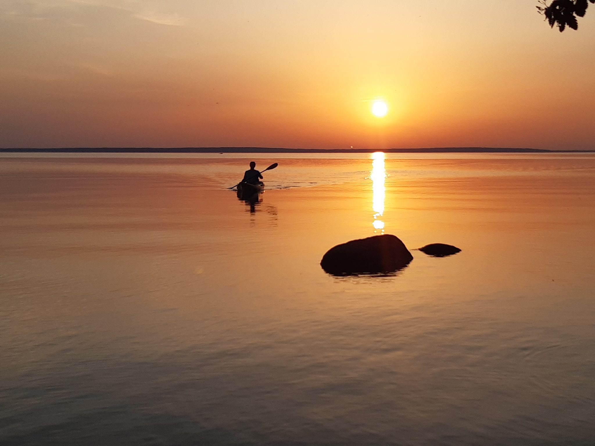 Kajakfahrer auf dem Wittensee im Abendrot, spiegelnde Wasseroberfläche, Stein im Vordergrund
