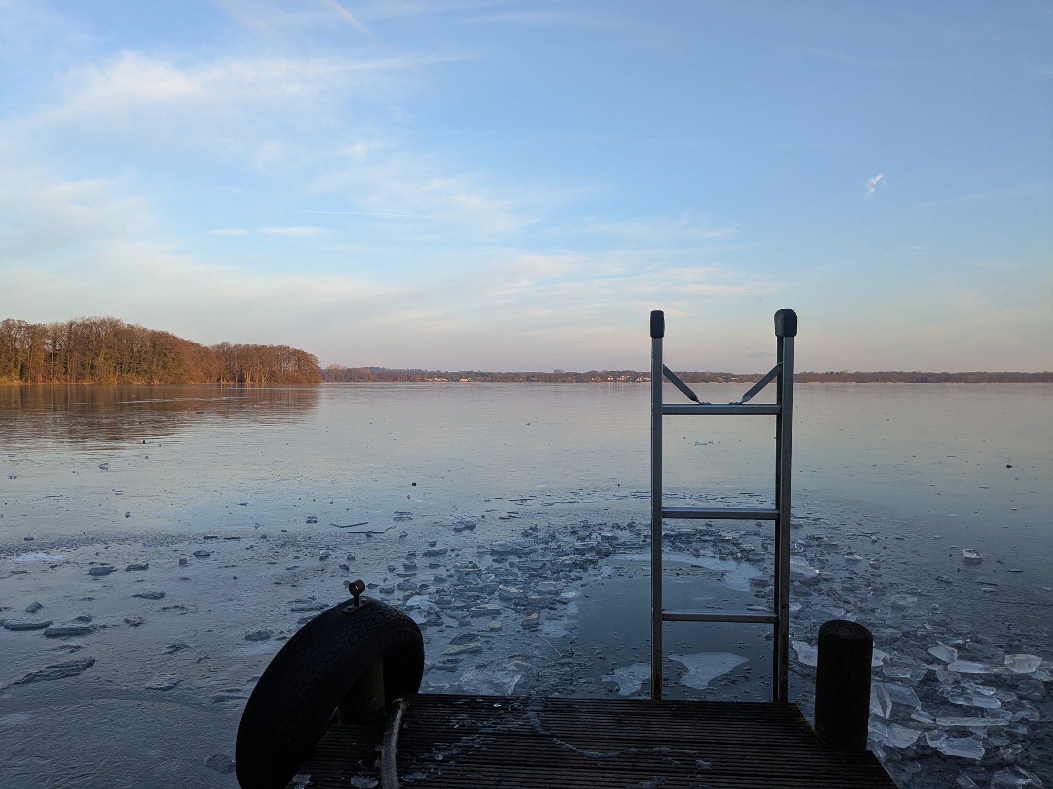 Bootssteg am Wittensee im Winter mit Einstiegsleiter und treibenden Eisschollen, Abendhimmel